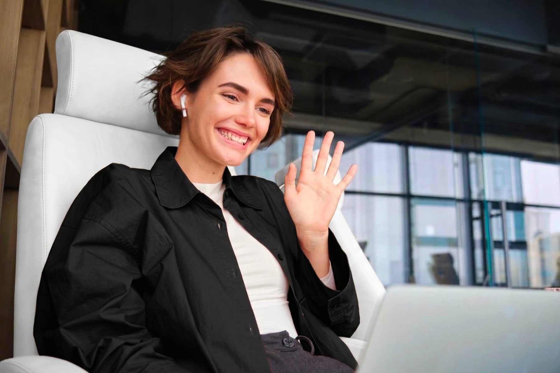 Professional waving on a video call from a desk